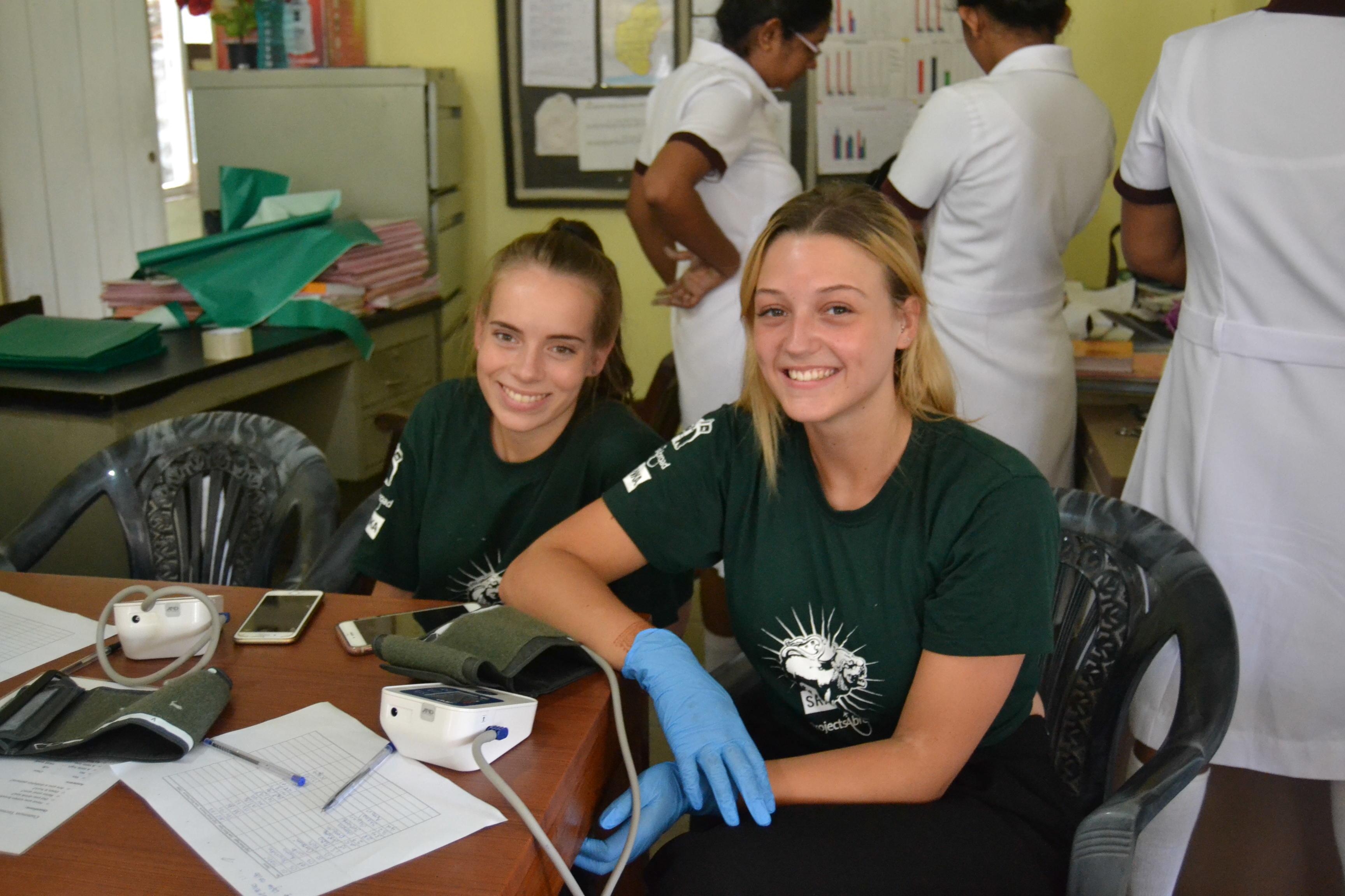 Projects Abroad Medicine and Healthcare interns at a medical outreach in a local rural community in Sri Lanka. Two medical interns take a break during a community outreach organised by Projects Abroad in Sri Lanka.